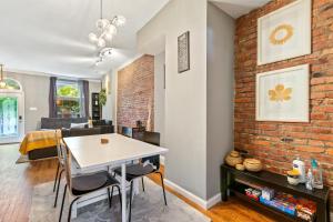 a living room with a white table and a brick wall at Pristine Townhouse With Rooftop Deck Near Canton! in Baltimore
