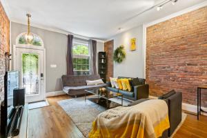 een woonkamer met een bank en een bakstenen muur bij Pristine Townhouse With Rooftop Deck Near Canton! in Baltimore