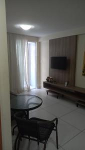Una sala de estar con una mesa y un televisor. en Israel Flat Tambaú - 213, en João Pessoa