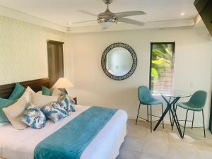 1 dormitorio con 1 cama, mesa y sillas en Tropical Retreat - Poolside Swimout - Ground Floor - Sea Temple Resort & Spa Port Douglas en Port Douglas