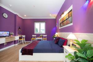 a purple bedroom with a bed and a table and chairs at Ben Thanh Station Hotel in Ho Chi Minh City