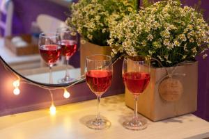 three glasses of wine sitting on a table with flowers at Ben Thanh Station Hotel in Ho Chi Minh City