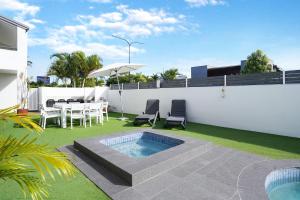 un patio trasero con piscina, mesa y sillas en Noosa Parade Holiday Inn en Noosa Heads