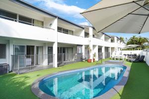 a swimming pool in front of a building with an umbrella at Noosa Parade Holiday Inn in Noosa Heads