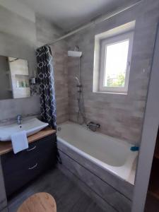 bagno con vasca, lavandino e finestra di Brook-Stone Beach Guesthouse a Sztutowo