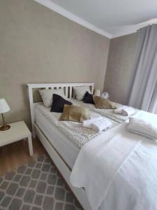 a white bedroom with two beds with pillows at Brook-Stone Beach Guesthouse in Sztutowo