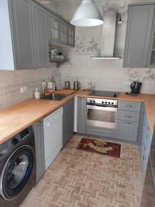 a kitchen with a washer and a sink and a dishwasher at Brook-Stone Beach Guesthouse in Sztutowo