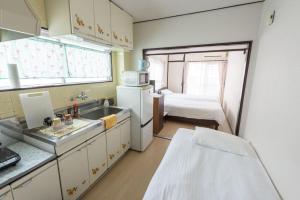 uma cozinha com um lavatório e uma cama num quarto em COCOSTAY Felice ココステイ フェリーチェ em Hiroshima