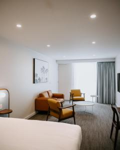 Peninsula Hotel Motel في أديلايد: غرفة في الفندق مع أريكة وكراسي