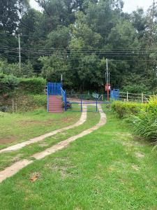 un parque infantil con una puerta azul en el césped en Cabaña Mamá Elia en Trinidad