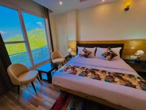 a bedroom with a bed and a large window at Hotel Pine Rock Mountain View, Mussoorie in Mussoorie