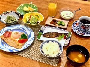 una mesa de madera con platos de comida y bebida en Hakuba Onsen Ryokan Shirouma-so, en Hakuba