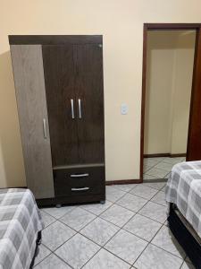a bedroom with a dresser and a bedroom with two beds at Solar de Bruna - Apartamento com 2 Qts - 1 Suíte - Garagem coberta - Wi-Fi - Netflix - Acomoda 6 pessoas a 70 metros da praia in Guarapari
