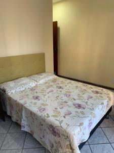 a bedroom with a bed with a floral bedspread at Solar de Bruna - Apartamento com 2 Qts - 1 Suíte - Garagem coberta - Wi-Fi - Netflix - Acomoda 6 pessoas a 70 metros da praia in Guarapari