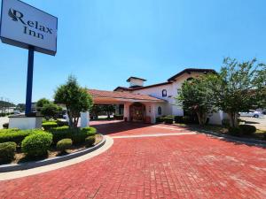 a building with a sign in front of a brick driveway at Relax Inn West Medical Center in Little Rock