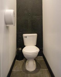 a white toilet in a bathroom with a black wall at RIO HOSTEL in Guatemala