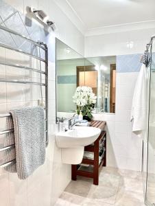 Baño blanco con lavabo y espejo en SilverWaters Waterfront Accommodation, en Morisset East