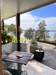 a patio with a table and a view of the water at SilverWaters Waterfront Accommodation Lake Macquarie in Morisset East