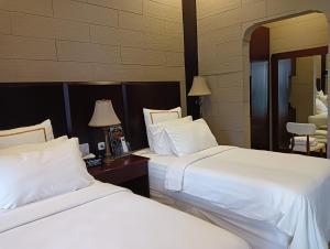 dos camas sentadas una al lado de la otra en una habitación de hotel en Alsalam Syariah Guesthouse, en Solo