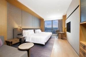 a hotel room with a bed and a large window at The Westin Zhongshan Guzhen in Zhongshan