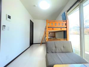 Credo Maison Kamakura - Vacation STAY 10394 في كاماكورا: غرفة نوم مع سرير بطابقين وأريكة