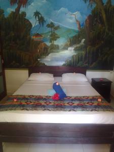 a bedroom with two beds with a painting on the wall at Kputra Homestay in Amed