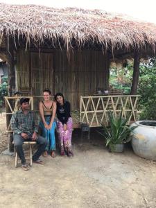 Un gruppo di persone seduti di fronte a una capanna di Battambang Eco Stay a Phumĭ Ândong Pring