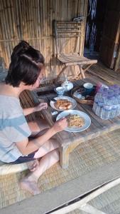 a woman sitting at a table with plates of food at Battambang Eco Stay in Phumĭ Ândong Pring