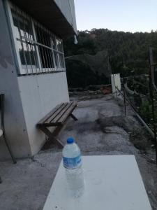 uma garrafa de água sentada num banco ao lado de um edifício em Orman ev em Ayvacık