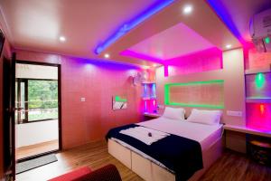 a bedroom with a bed with pink and green lights at Angel Blue Houseboat Alapuzha in Alleppey