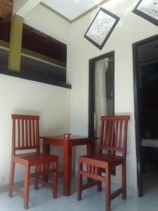 2 sillas de madera sentadas en una habitación con espejo en Kputra Homestay, en Amed