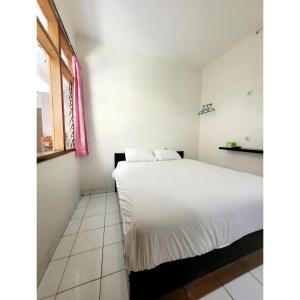 1 dormitorio con cama blanca y ventana en Teratai Residence, en Bandung