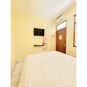 1 dormitorio con 1 cama y TV en la pared en Teratai Residence, en Bandung