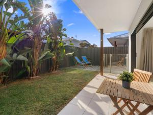 a backyard with a wooden table and a fence at Beach Pad on Nautilus in Kingscliff