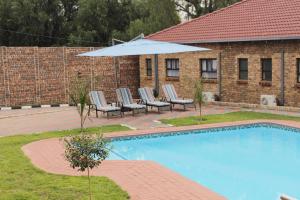 a group of chairs and an umbrella next to a pool at EMPEROR LODGE AND TOURS in Germiston