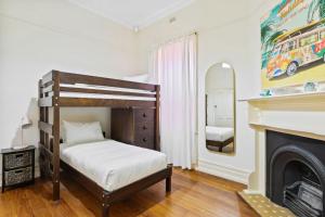 a bedroom with a bunk bed and a fireplace at Belle Escapes - Glenelg Cottage by the Marina in Glenelg