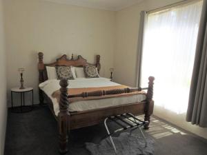 a bedroom with a bed with a wooden frame and a window at The Apartment - Moyston in Moyston