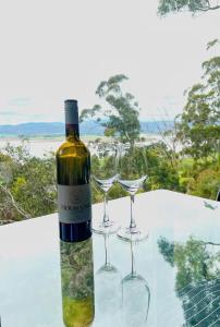 Cloud Nine Apartment @ Tamar Ridge في Grindelwald: زجاجة من النبيذ وكأسين من النبيذ على الطاولة