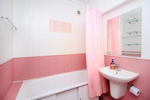 ein rosafarbenes Badezimmer mit einem Waschbecken, einer Badewanne und einem Waschbecken in der Unterkunft Great location Arbat, Zhibek zholy 81 & drinking water in Almaty