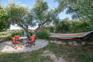 una hamaca en un jardín con 2 sillas y una mesa en Villa Zoi, en Méson Yerakaríon