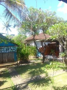 a house with a tree in front of it at Kputra Homestay in Amed