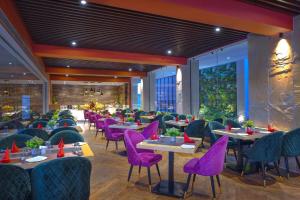 a dining room with purple chairs and tables at Royale Sarovar Portico Agra in Agra