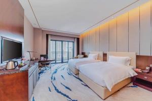 a hotel room with two beds and a television at Ramada By Wyndham Huizhou South in Huizhou