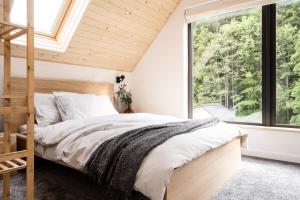 a bedroom with a bed and a large window at Babia Rest - całoroczny domek z balią z jacuzzi in Zawoja