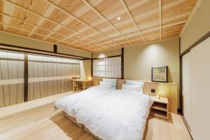 a bedroom with a large white bed and wooden ceilings at Ryokan Kigusuriya in Nantan city