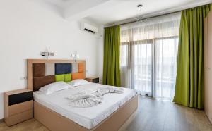 a bedroom with a large bed with green curtains at SnS Apartament Regal in Mamaia
