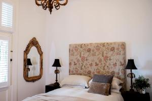 a bedroom with a bed with a floral headboard and a mirror at The Doncaster in Braidwood