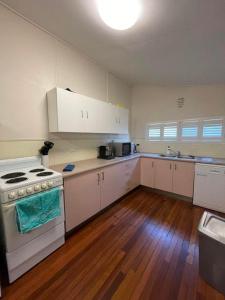 a kitchen with white cabinets and a stove at Keppel Cottage - 7 Limpus Avenue Keppel Sands in Keppel Sands