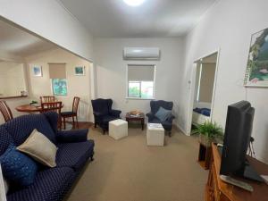 a living room with a couch and chairs and a tv at Keppel Cottage - 7 Limpus Avenue Keppel Sands in Keppel Sands +3 photos