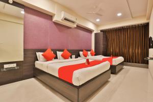 two beds in a room with red and white at Hotel Royal Rituals Vesu in Surat